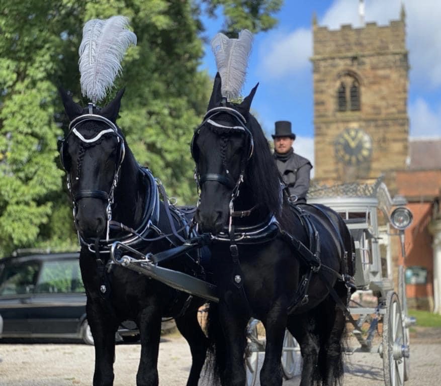 Horse-drawn funeral carriage outside a church